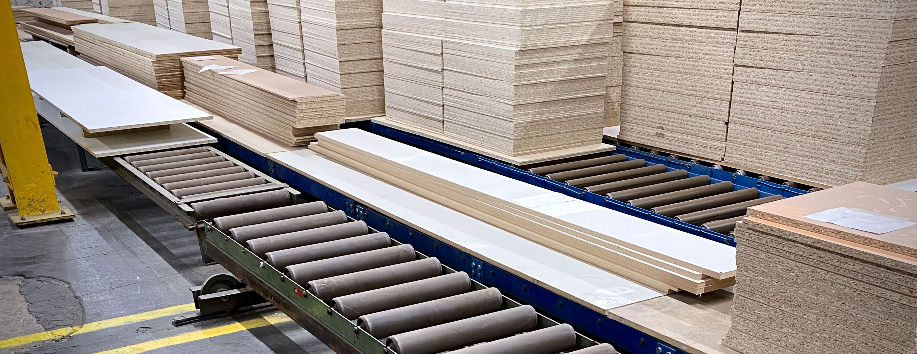 Stacks of machined chipboard panels on roller tracking  